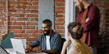 Three people meeting around a laptop computer