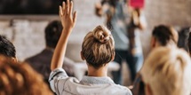 Student with a raised hand viewed from the back